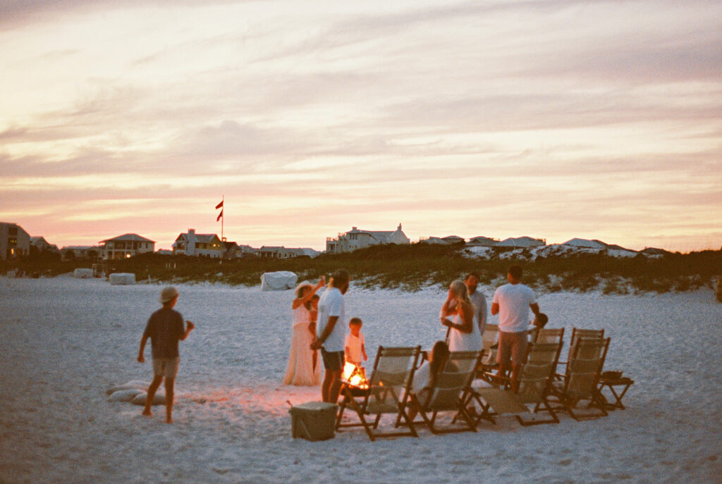 Friends gathered around a beach bonfire sharing stories after sunset. The bonfire was setup in Santa Rosa Beach, FL 30A Florida.