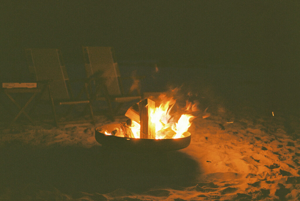A beach bonfire after sunset in Santa Rosa Beach, Florida. The photo is dimly lit bonfire.